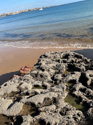 Picture of the ocean with shoes sitting on a rock