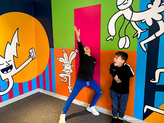 Two boys standing in front of a brightly coloured wall