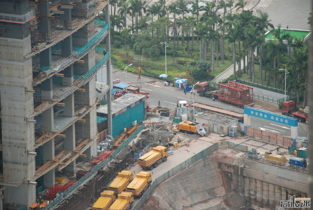 Photo of yellow trucks waiting down on the street by the building under construction