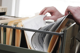 Pic of open filing cabinet with hands going through official documents in folders