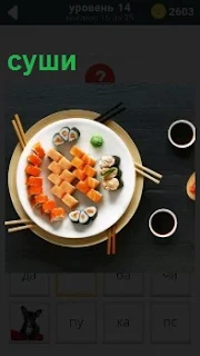 В тарелке лежит приготовленное блюдо суши с палочками для еды и вокруг чашки с напитком