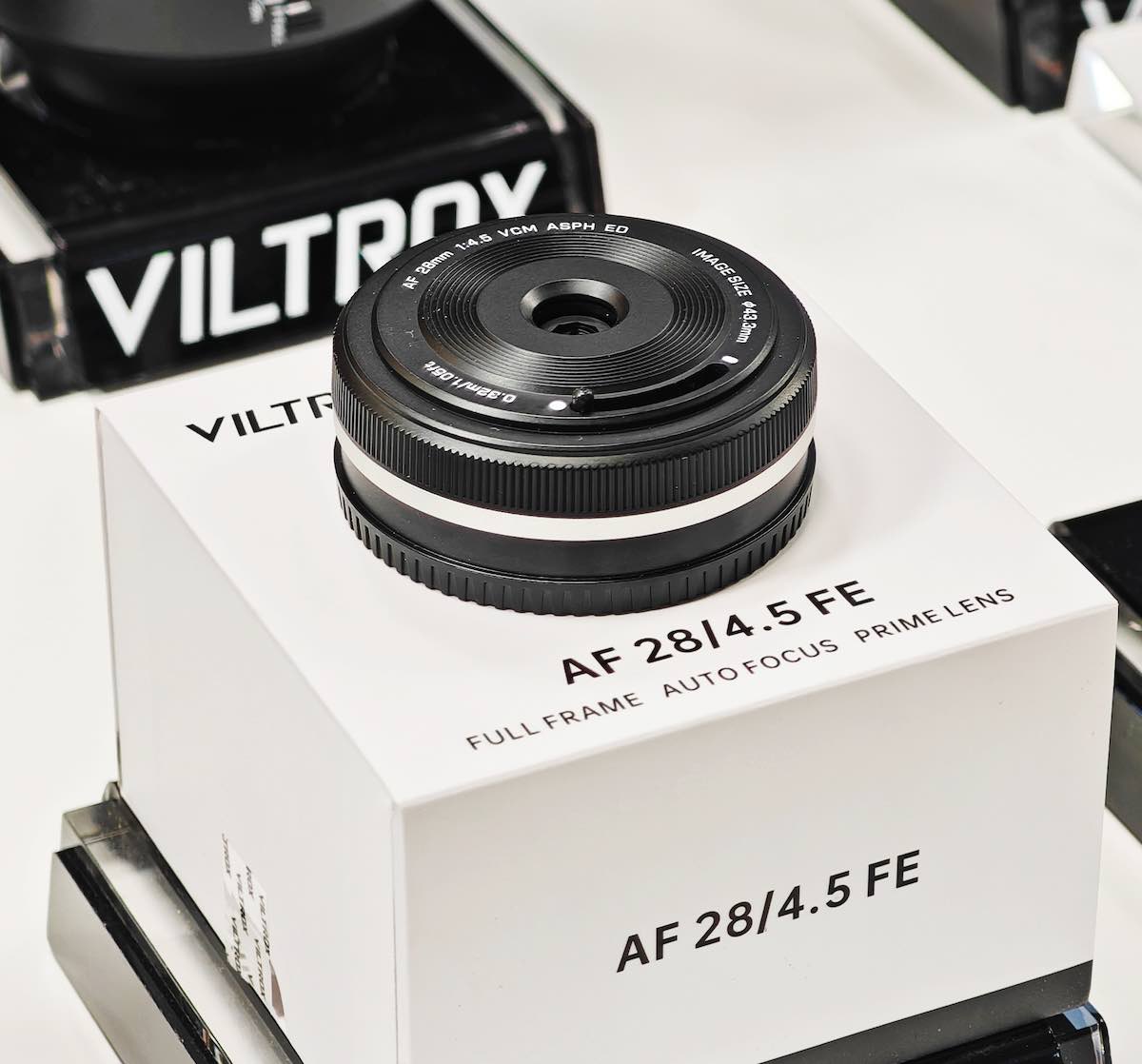 Объектив Viltrox AF 28mm f/4.5 VCM лежит на коробке из-под объектива