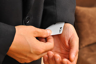 Photo of White Male in Black Suit Pulling Ace of Clubs from His Sleeve