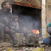 A man and children sit around a fire in the besieged area of Homs in Syria