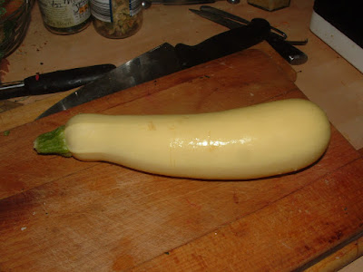 A yellow zucchini on a wooden cutting board