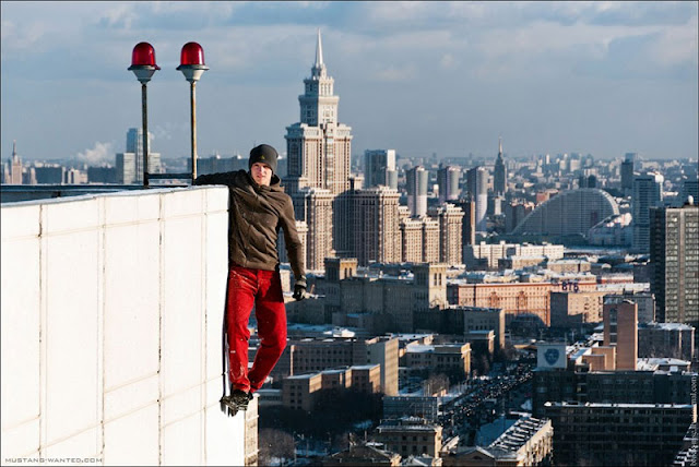 Man hanging from the building with Moscow skyline in the background