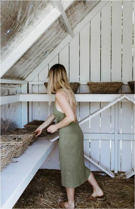 woman in a green dress standing in a barn