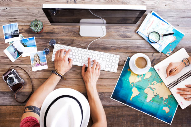 A person looking at a map and laptop, symbolizing travel planning and research.