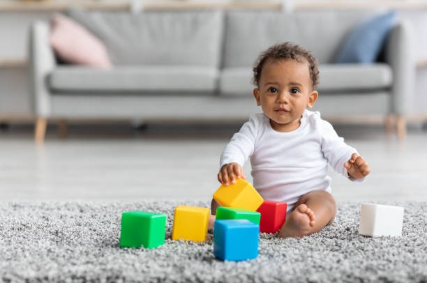 Adorable black infant baby playing with toy.