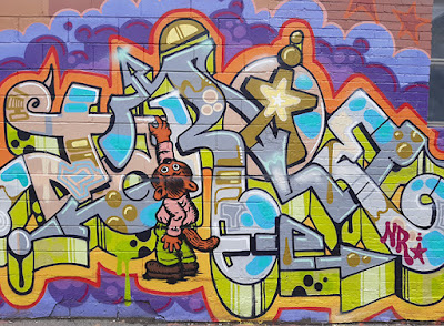 Colourful wildstyle graffiti on a brick wall - includes a cartoon cat with a spray can