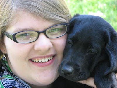 Taelor Michehl with black Lab puppy