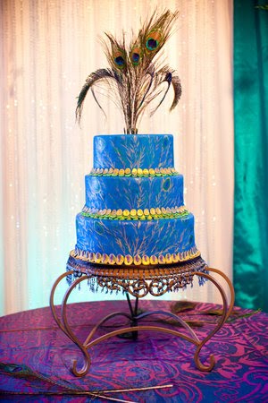 Three tier white round wedding cake with a blue peacock topper who's sugar