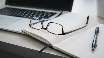 Internet business work station with books, pen, eye glasses and a computer.