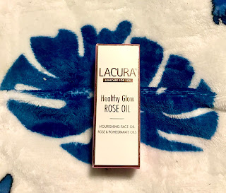 A rectangular white box with lacuna healthy glow rose oil in rose gold font on a bright background