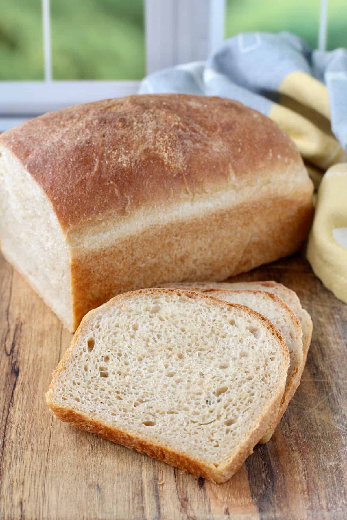 Whole wheat and bread flour loaf sliced on a cutting board.