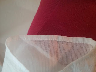 Wrist area of a sleeve; the material is a sheer white cotton with a subtle stripe, the hem is folded over 1/4" twice, and stitched with 20+ running stitches to the inch.