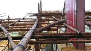 Image of bamboo scaffolding around a small building in Hong Kong from directly beside the bottom supports.