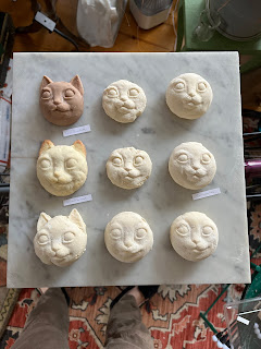 Nine cat head cookies on parchment paper.