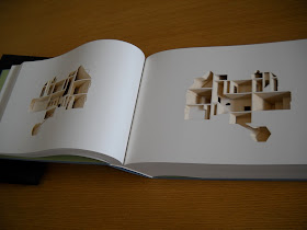 An open book. The pages are blanked have elements cut out to create the image of a house layout.