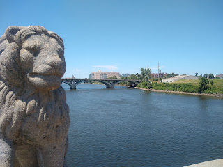 concrete lion by river, bridge in backgound