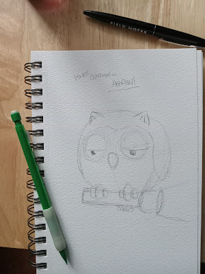 A ringbound watercolor sketchbook lays most of the way on a pale wooden tray, a green mechanical pencil resting on a page where a faint sketch of an exhausted owl has been drawn. The round owl is holding a flashlight. The words "Power Outage Again!" are over his head. Above the sketchbook is a black Field Notes branded pen.