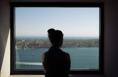 An image of alone girl from back looking towards the sea shore from her room window and expressing her loneliness- sad girl dp