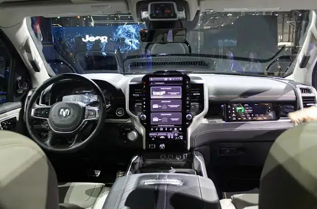 The interior of the 2024 Ram 1500 REV, including three screens and a steering wheel.
