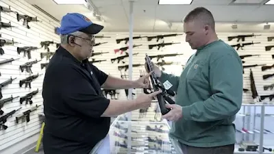 Roger Krahl, president of RGuns, left, gives information to Zack Johnson about an RGuns-brand TRR15 model rifle at Krahl's gun store in Carpentersville, Illinois. (Getty Images)