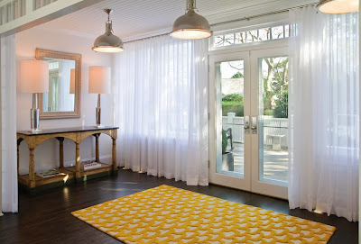 from inside, the main entry of the house is glass windows and doors with white wood frame decorated with curtains