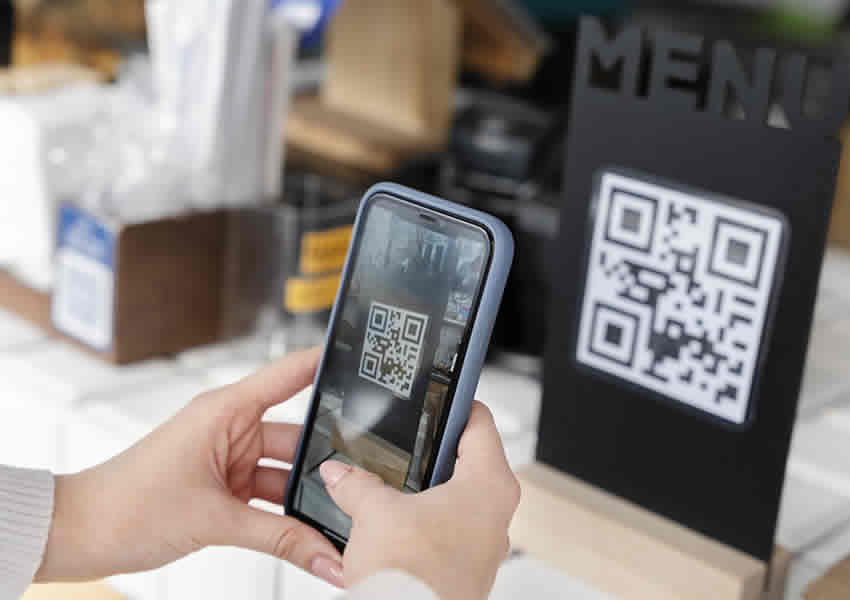 Imagem mostra duas mãos segurando um Smartphone fazendo a leitura de um QR Cod de pagamento pix.