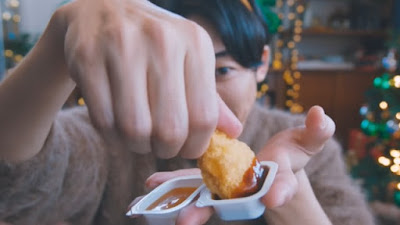 Man dipping Chicken Nugget in McDonald's Japan's Black Truffle Steak Sauce and holding an open cup of Lobster Butter Sauce..