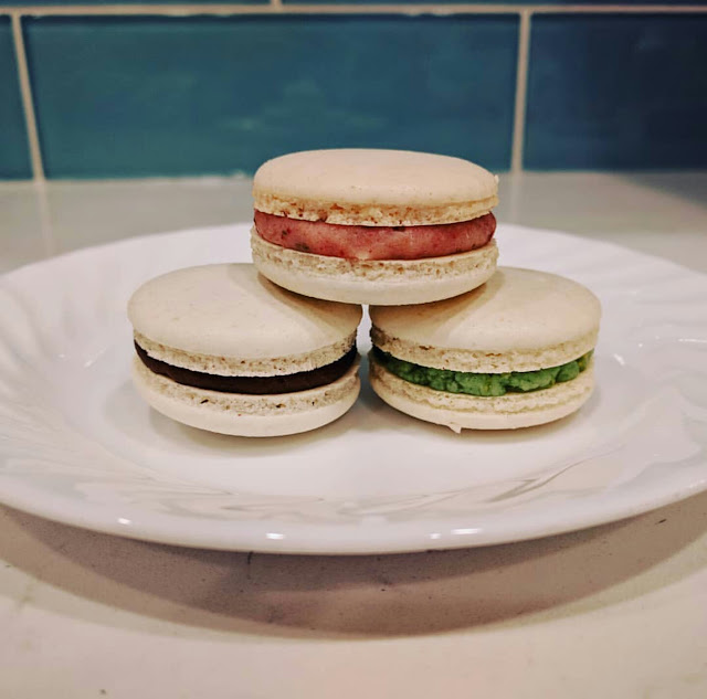 A trifecta of macarons - strawberry, nutella and pistachio on a white plate