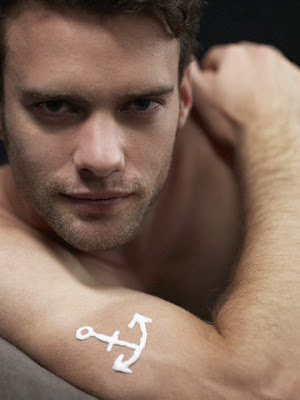 White anchor tattoo on a man's upper arm.