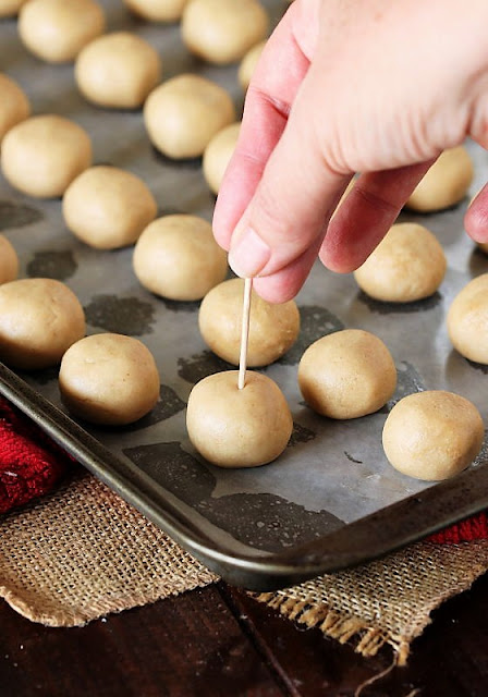Sticking Wooden Pick Into Peanut Butter Ball to Make Buckeyes Image
