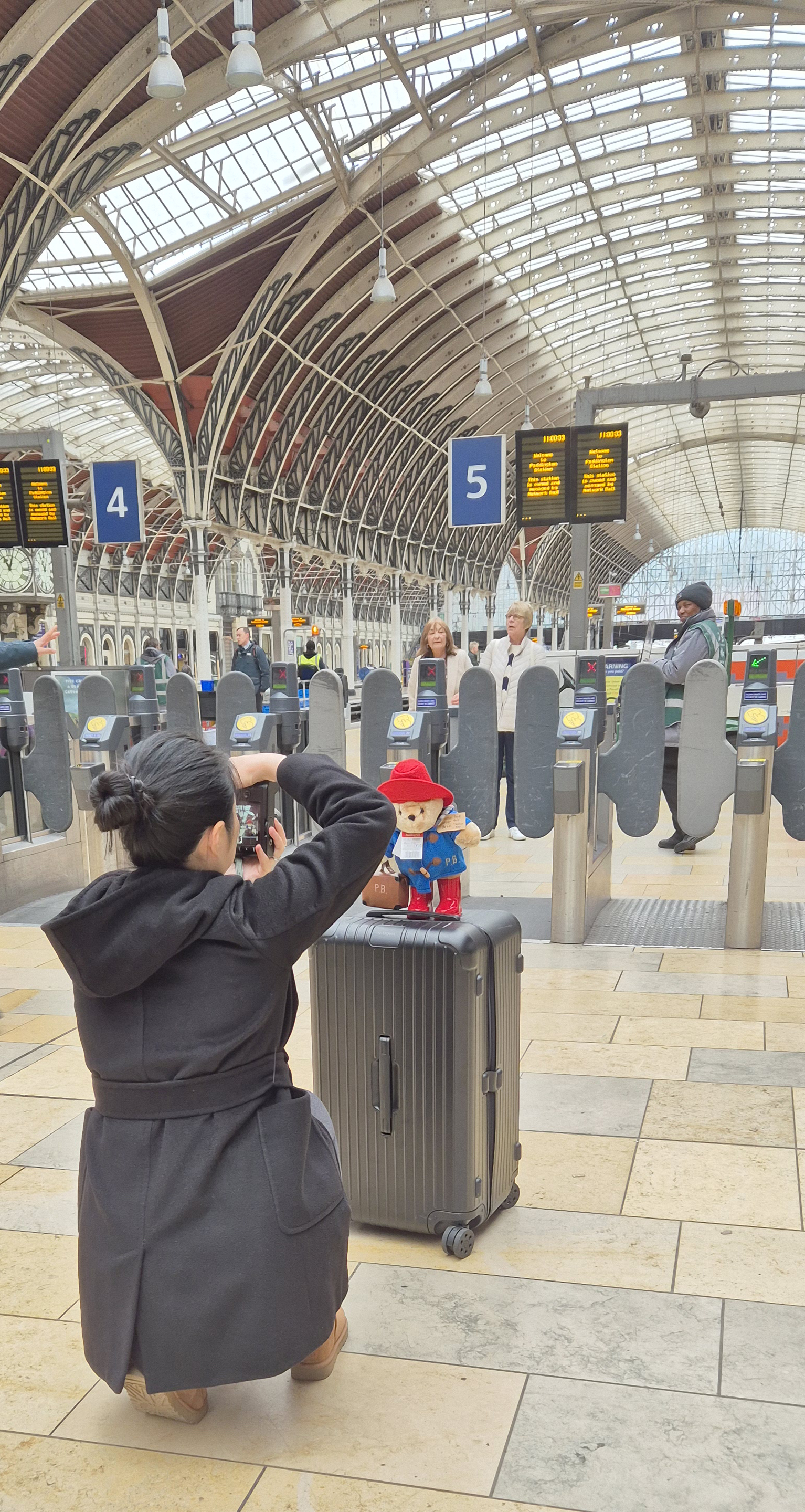 Woman photographing Paddington Station with bear in foreground