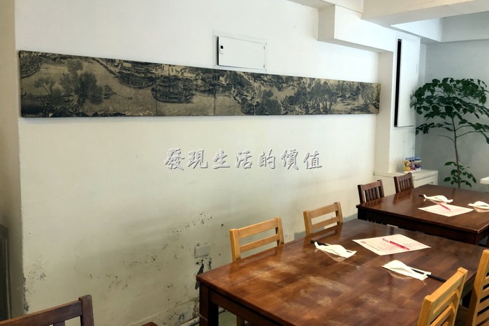 台北東湖【喜相逢麵館】內部裝潢一隅，基本上就是幾張桌子，然後牆壁上有一幅好像是清明上河圖的中國畫（沒仔細看）。