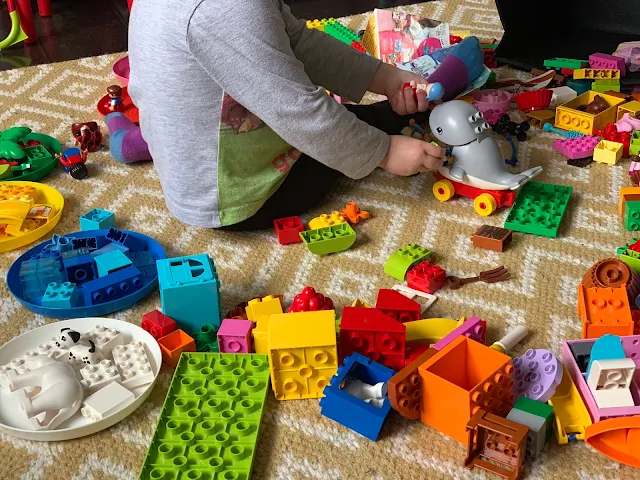 A toddler surrounded by DUPLO LEGO