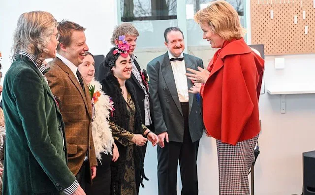 Queen Mathilde wore an coral orange silk blouse by Natan. Natan coral, bright red wool coat. Natan checked trousers