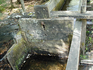 A wood gate in the flume controls the amount of water that goes to the water wheel.