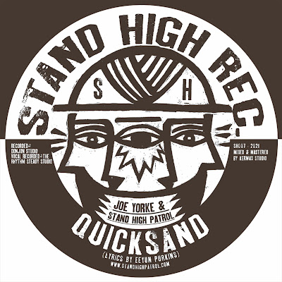 The paper label for the single features the artist name, imprint (Stand High Records), and illustration of three faces (one looking forward, another left, and the other right).