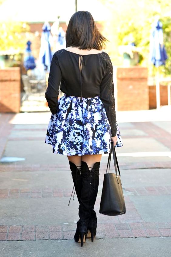 Woman wearing black top, floral mini skirt and black over the knee boots