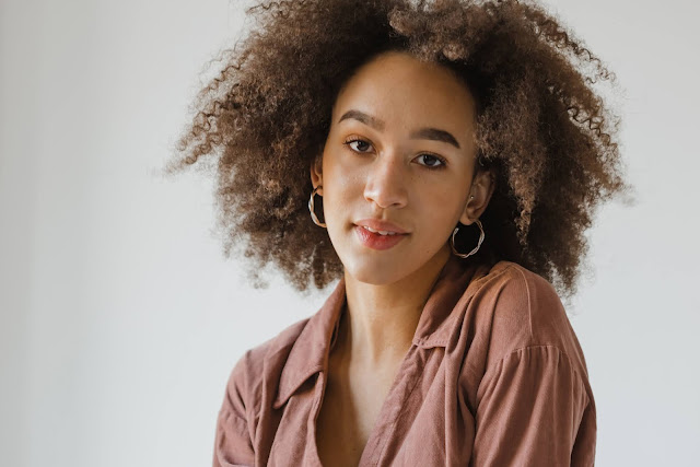 Curly haired brunette woman wearing hoop earrings.