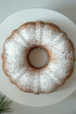 Bezuckerter Marmorgugelhupf von oben fotografiert auf einer weißen Kuchenplatte.