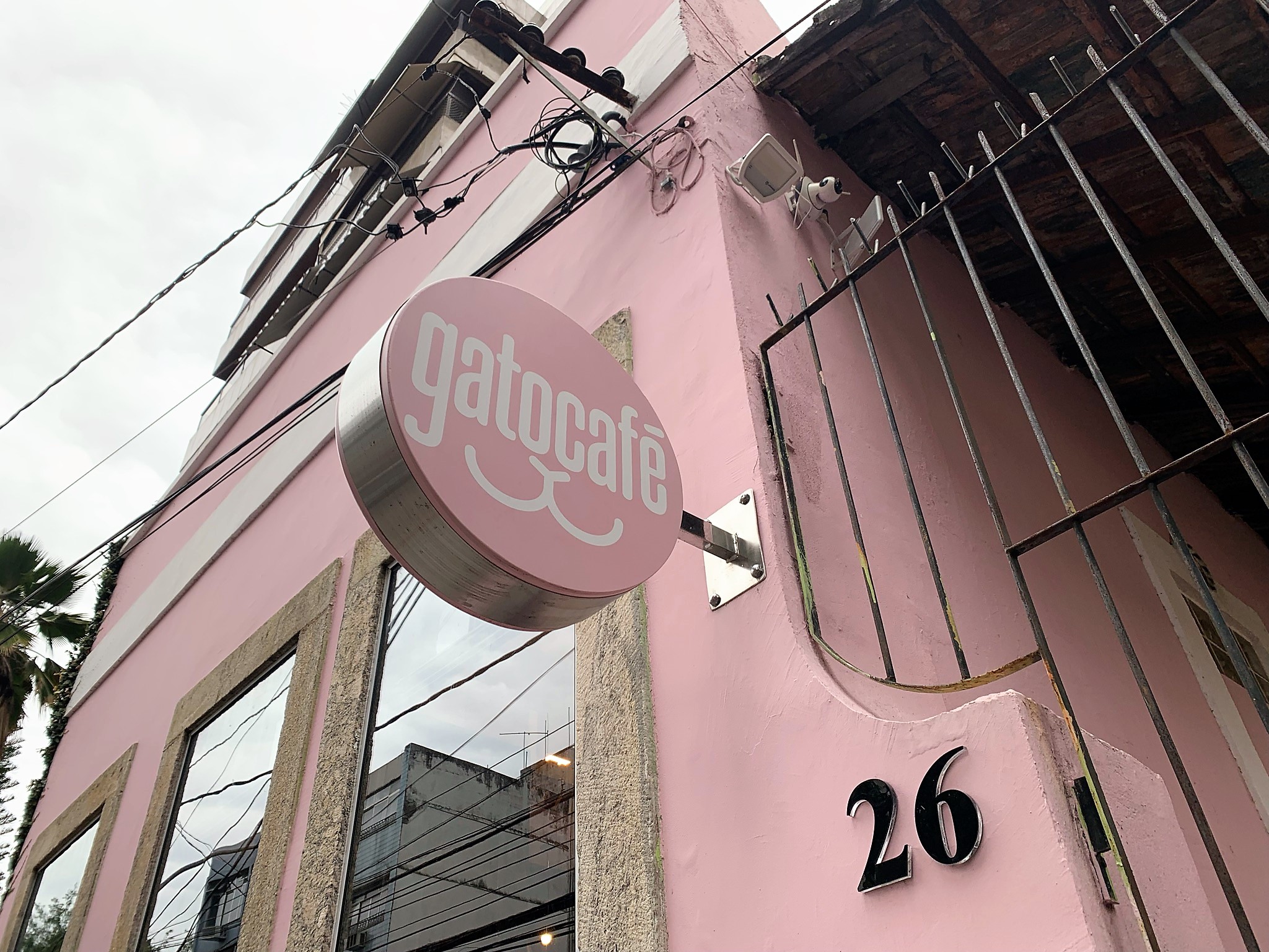 Foto da fachada do casarão do GatoCafé em rosa com destaque para logo da cafeteria