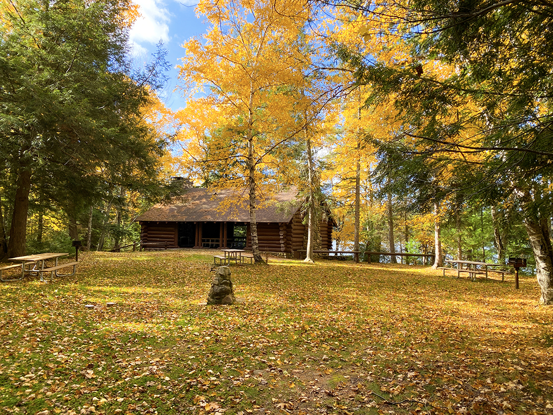 Grassy lawn with autumn leaves in front of timber frame shelter