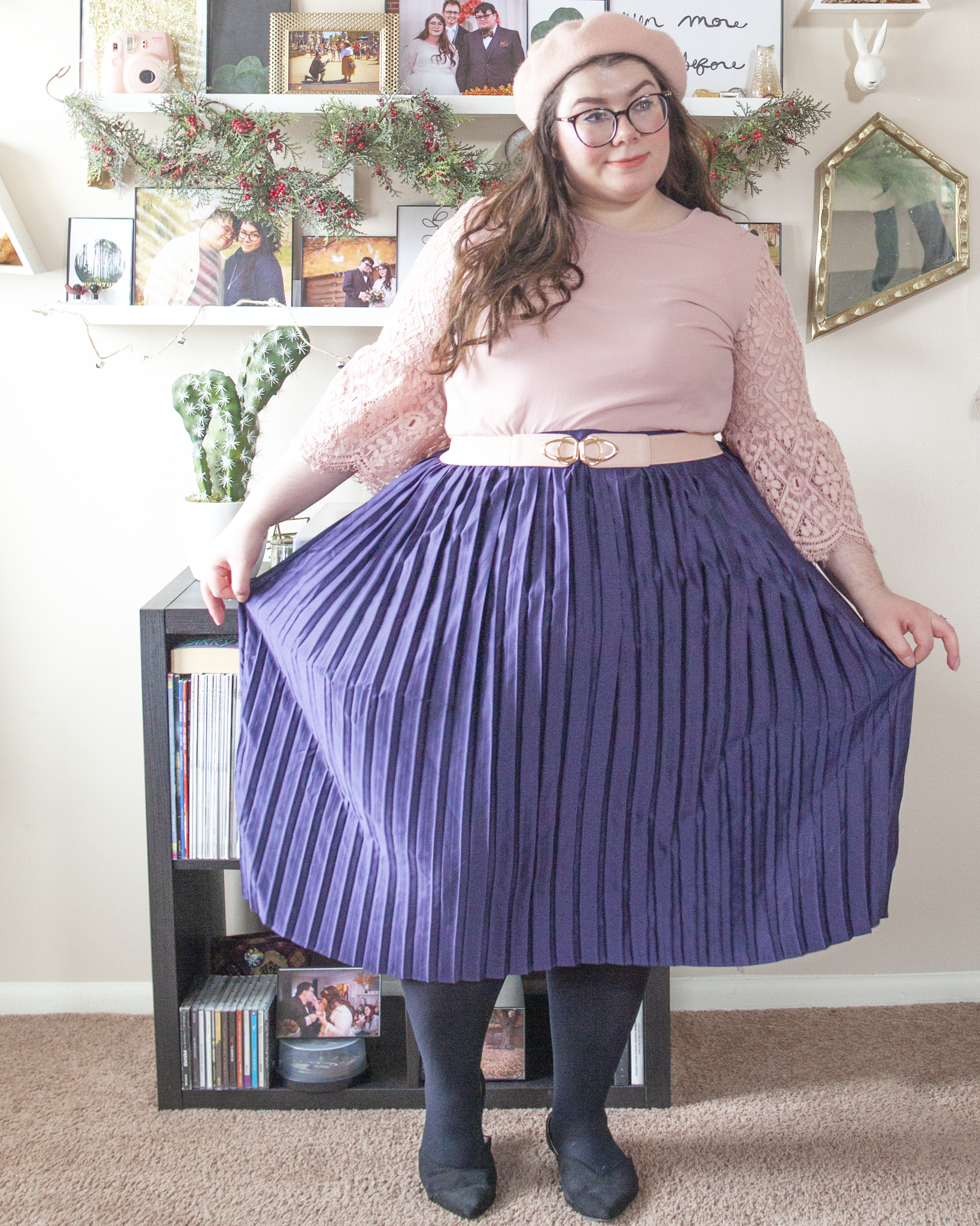 An outfit consisting of a pastel pink beret, a pastel pink dress with lace 3/4 length flounce sleeves tucked into a navy blue pleated midi skirt and black pointed toe slingback flats.