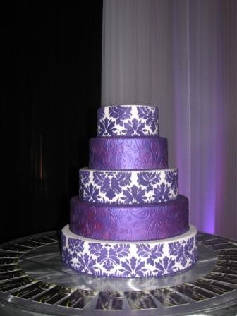 Three tier square white wedding cake with purple damask pattern