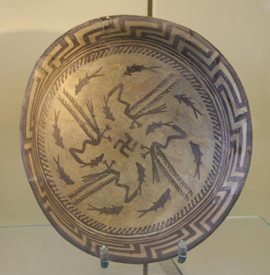 Ceramic bowl from Samarra, Iraq. Swastika in the center, surrounded by cranes eating fish, surrounded by swimming fish and geometric patterns.