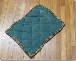 Small green quilt made of old green towels. Edges are irregular.