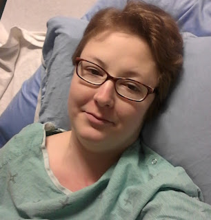 Me in my green hospital gown, laying in bed after surgery. 